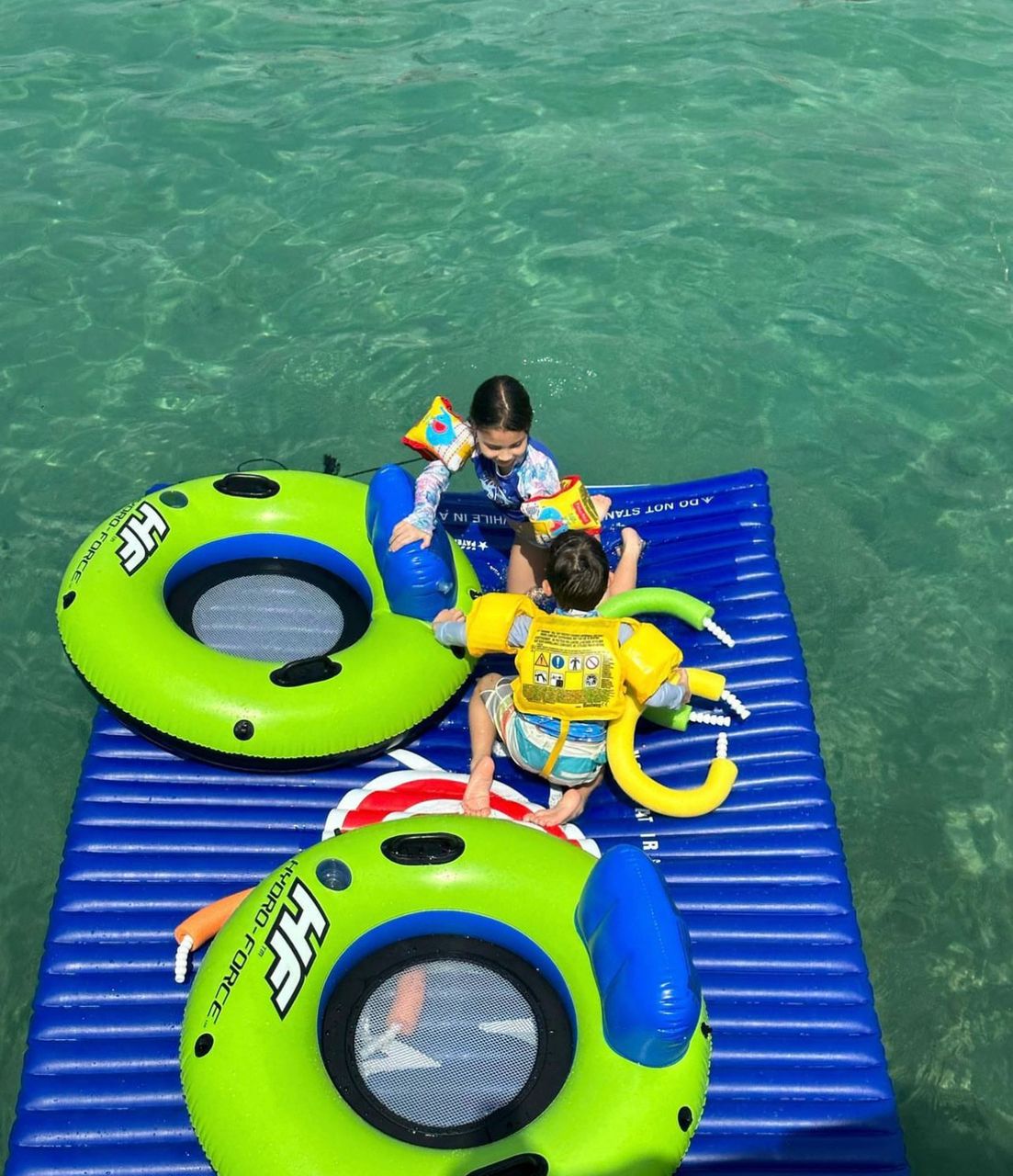 Bambini su galleggianti in acque turchesi